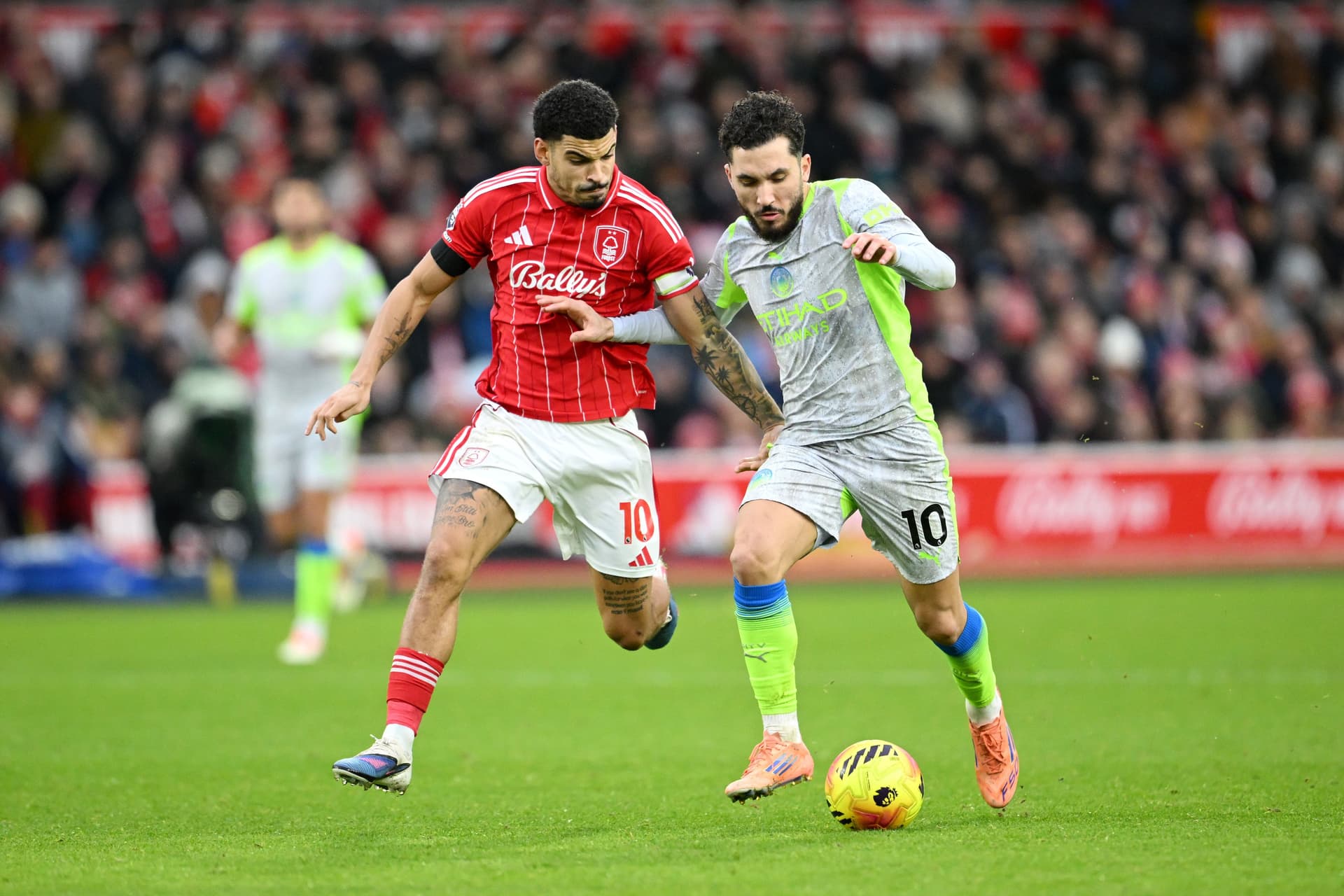 Rayan Cherki of Manchester City is challenged by Morgan Gibbs-White of Nottingham Forest
